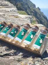 Load image into Gallery viewer, Map of Ireland jewellery in Love Ireland Gift Co glass gift jars on a clifftop

